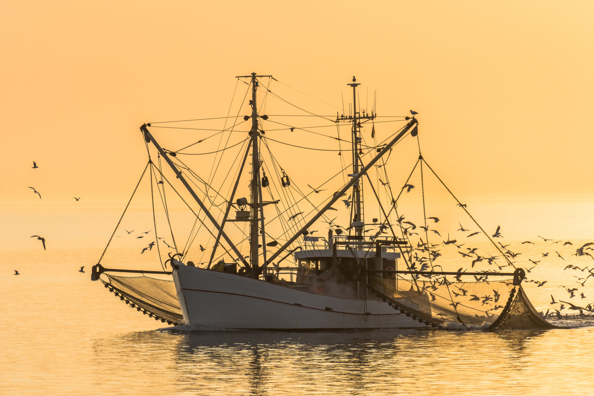 Fischerboot mit Netzen bei Sonnenuntergang